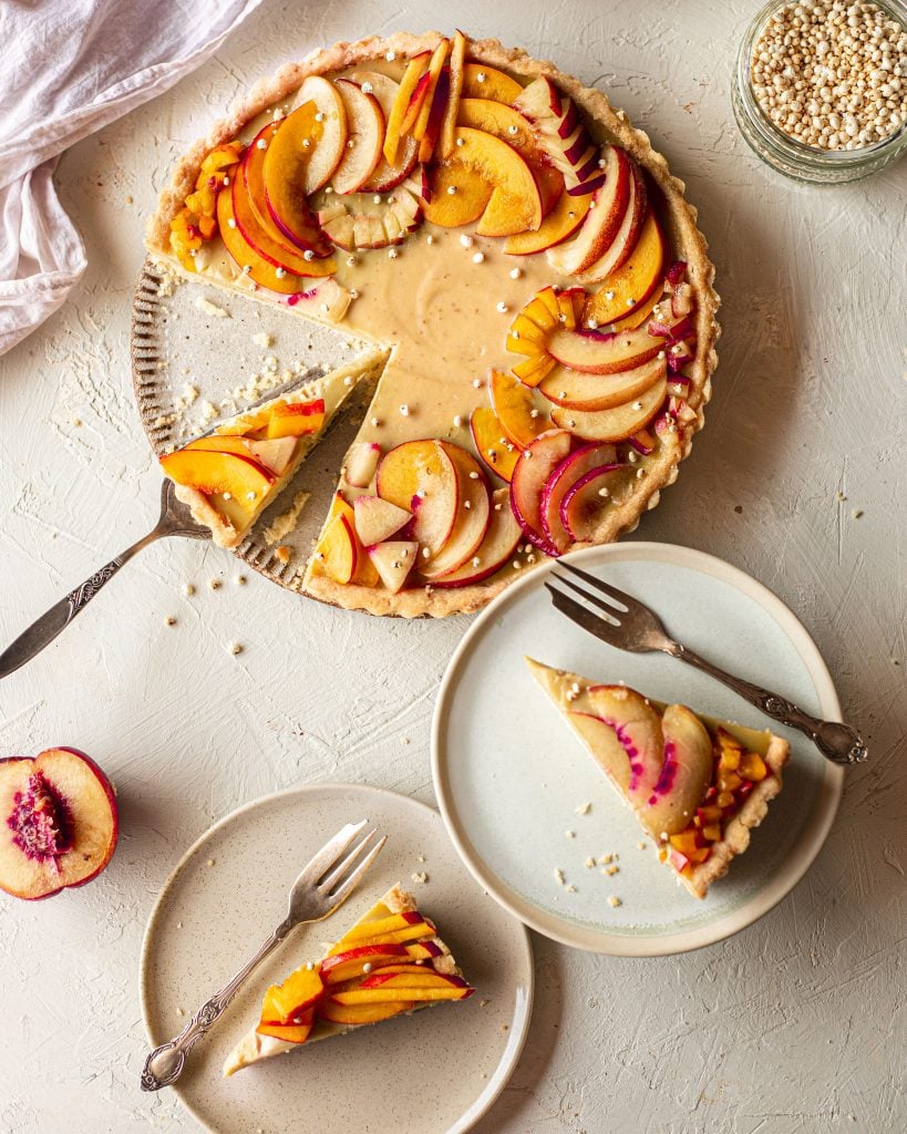 Flatlay of nectarine tart with a few slices on plates.