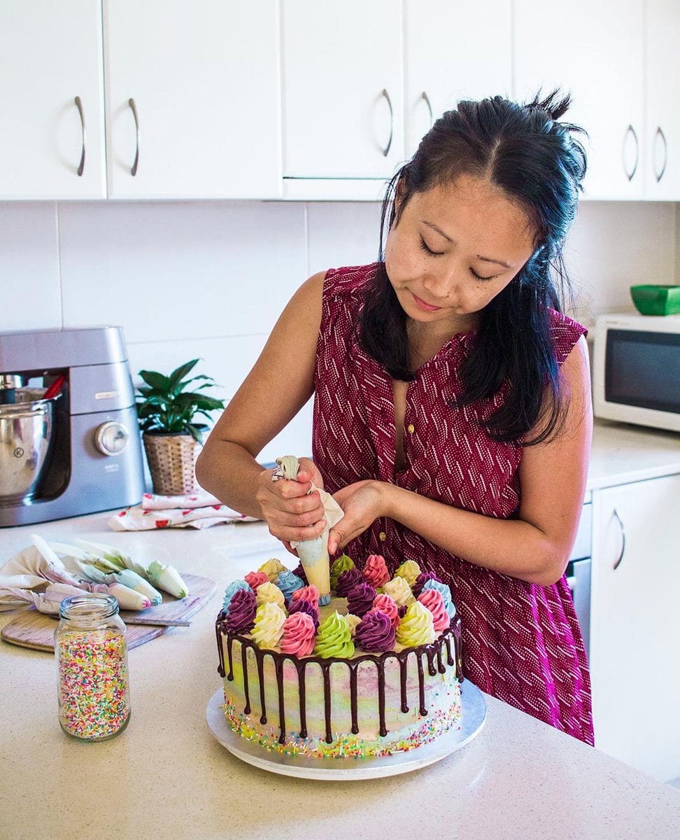 Author decorating a cake in a kitchen.