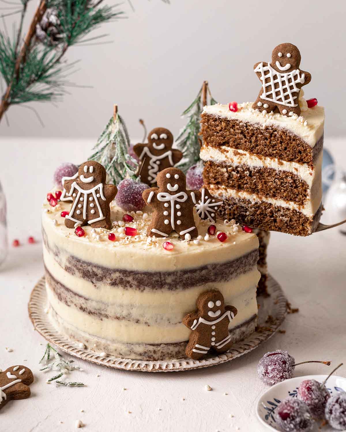 Decorated 3-layered gingerbread cake with a slice lifted up revealing layers of cake and frosting.