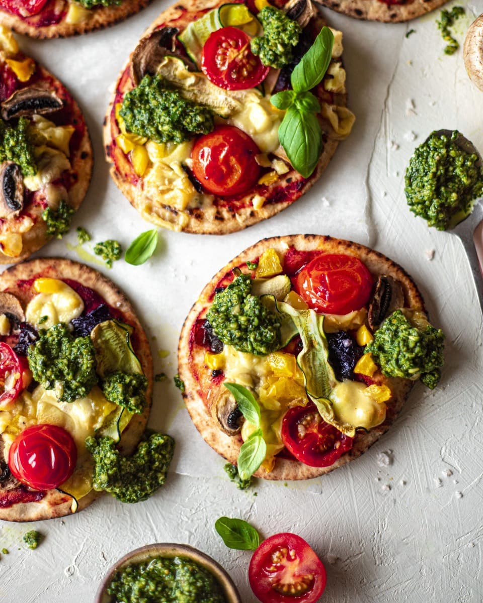 Close up of veggie pita pizza with dollops of pesto.