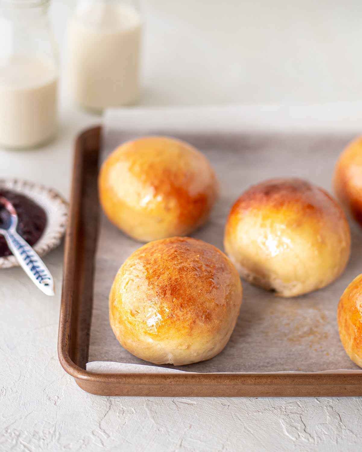 Vegan brioche buns on lined baking tray.