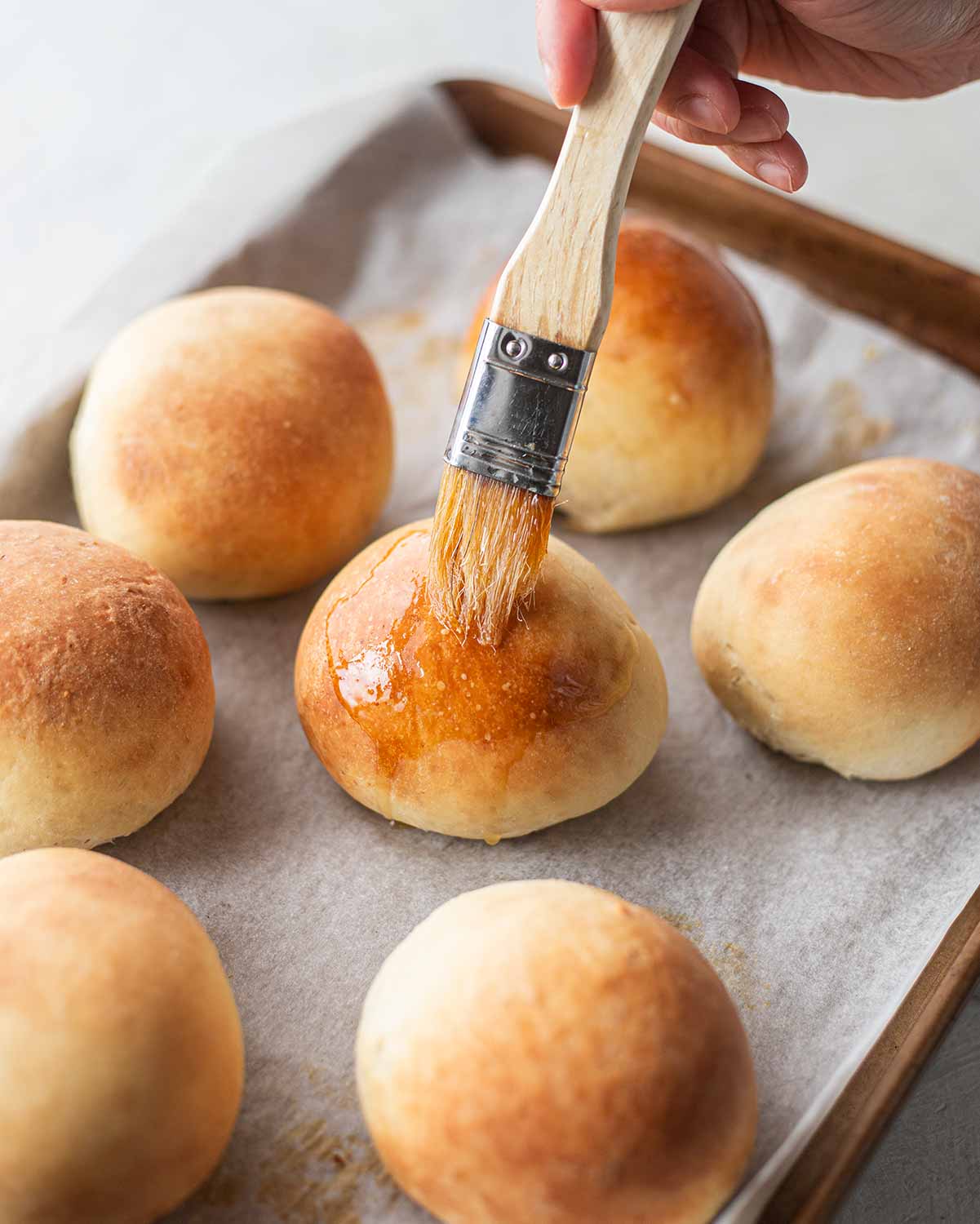 Brushing the vegan buns with a sugar glaze.