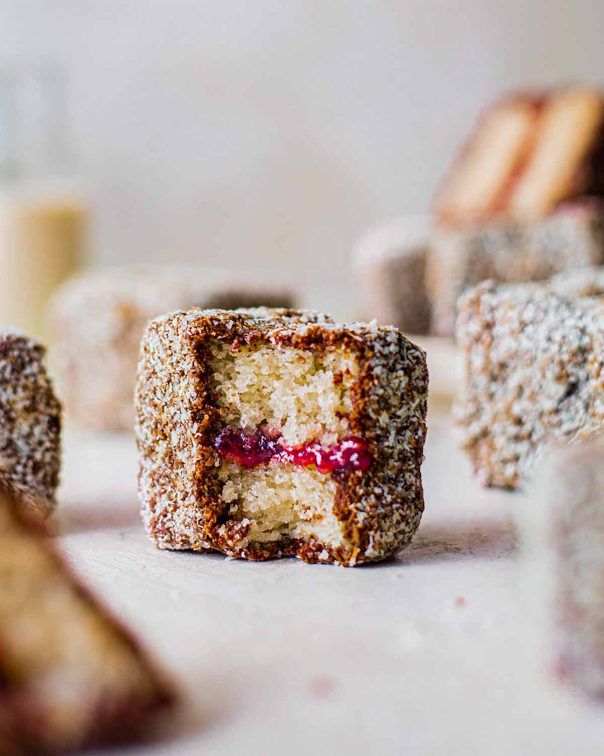 Cross section of vegan lamington showing fluffy vegan vanilla sponge and raspberry jam.