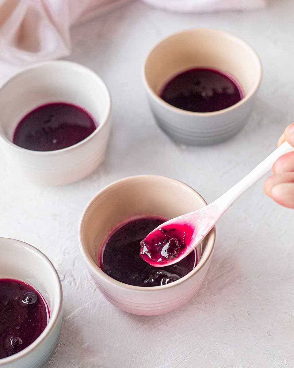 Pouring the blackcurrant jam into mini ramekins for the vegan self-saucing puddings.