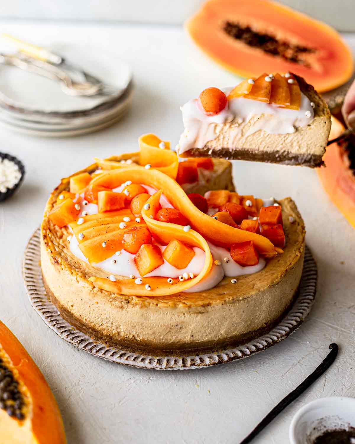 Papaya vanilla cheesecake on plate with slice lifted out showing its creamy texture.