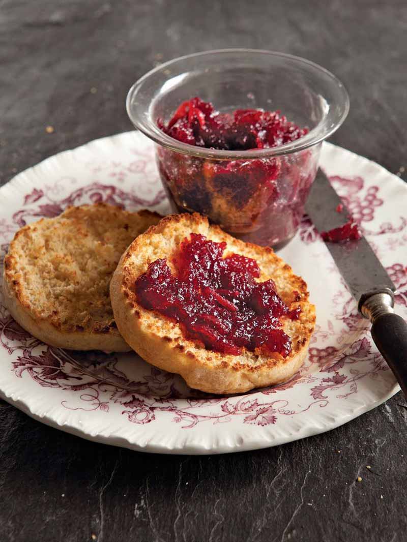 Sourdough English Muffin cut in half with chunky red jam on one half.