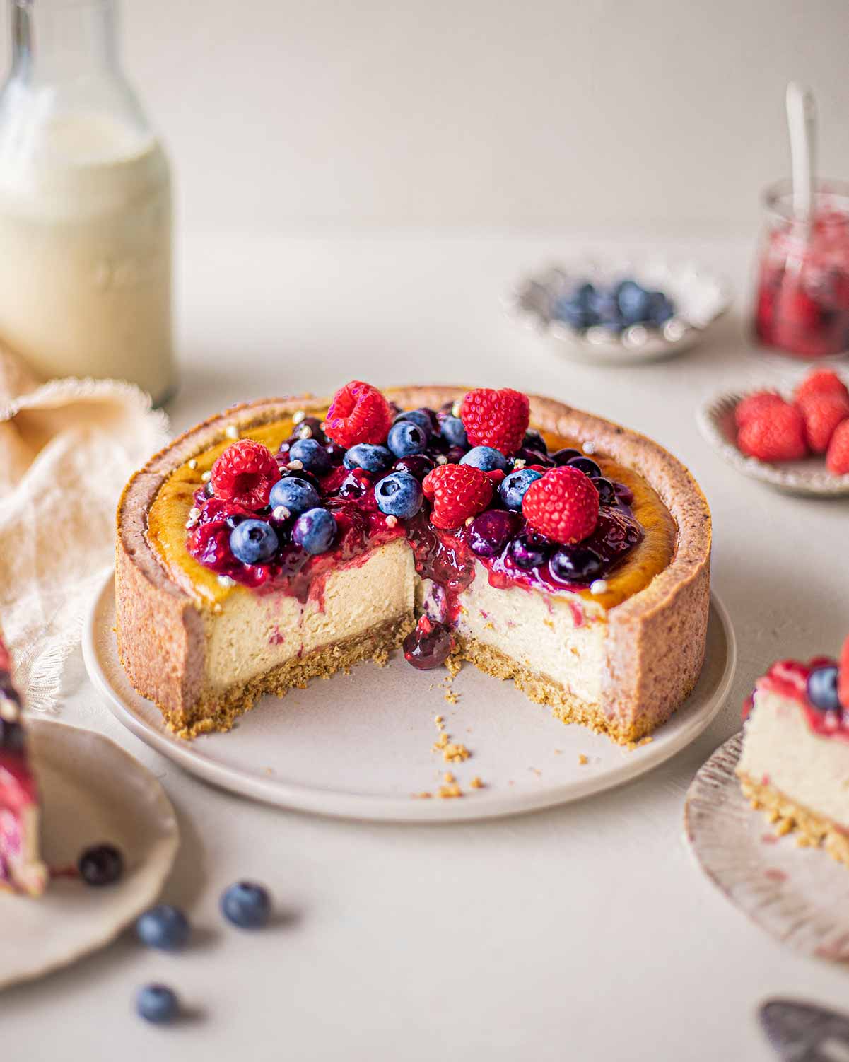 Cross section of baked cheesecake with drip of berry compote on luscious creamy cheesecake filling.