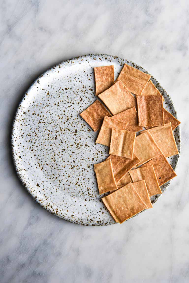 Vegan gluten free sourdough crackers arranged on half of a ceramic hand made plate.