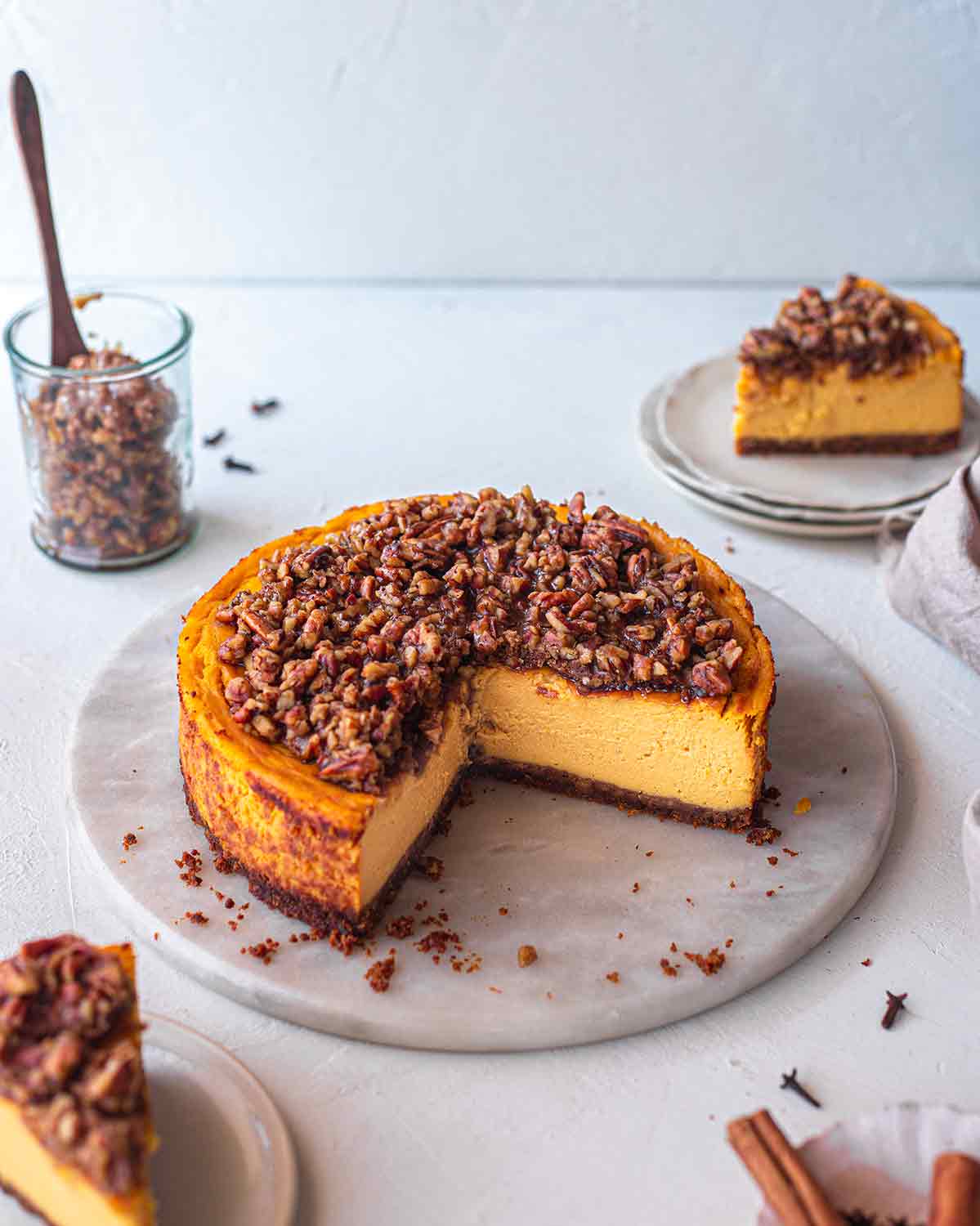 Cross section of baked vegan pumpkin cheesecake with a pecan crumble on a serving platter.