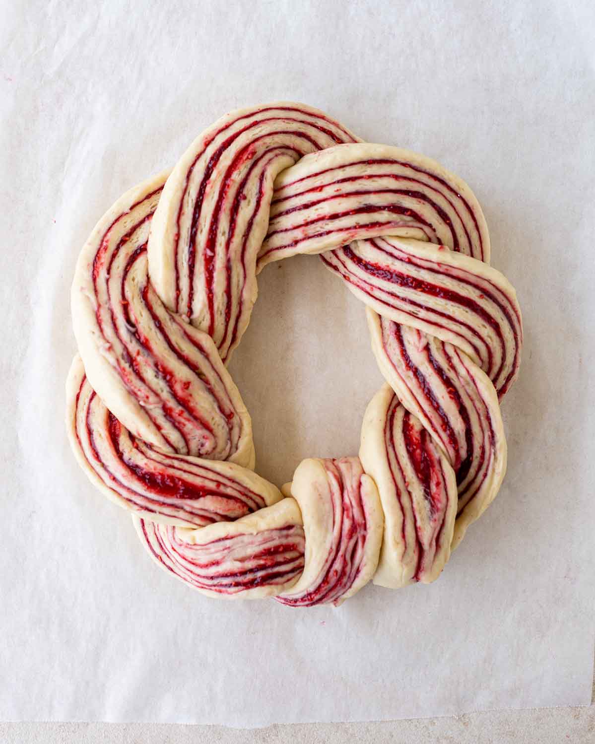 Unbaked raspberry wreath on baking paper.