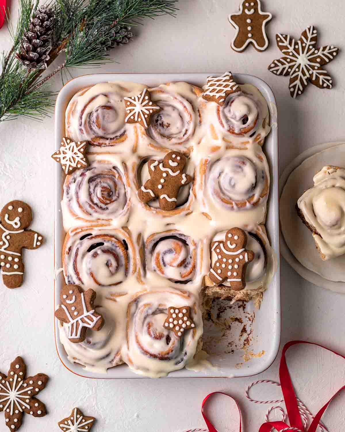 Vegan gingerbread cinnamon rolls in baking tray with gingerbread cookies on top.