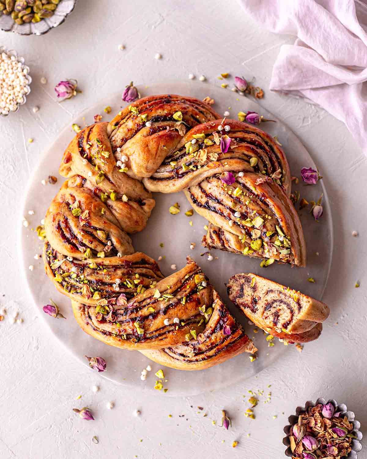 Christmas wreath bread on serving platter with a small slice coming out showing the beautiful swirls of Christmas fruit mince.