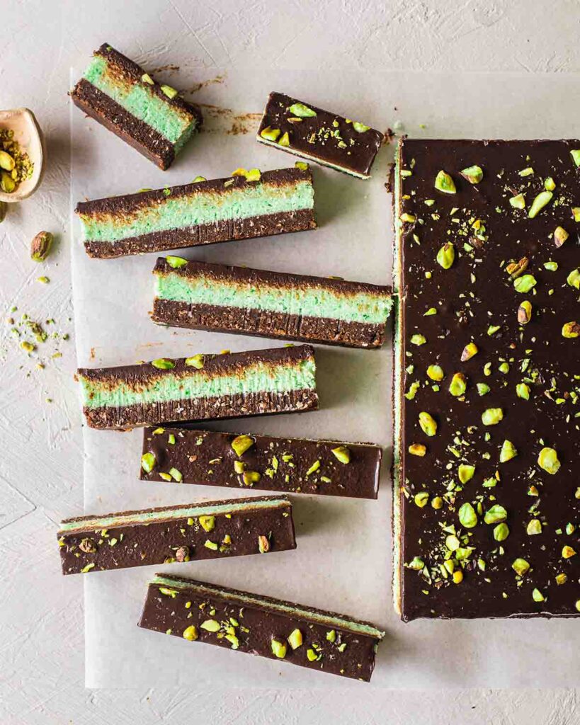 Flatlay of scattered chocolate mint bars showing 3 distinct layers. into small thin slices revealing its 3 layers.