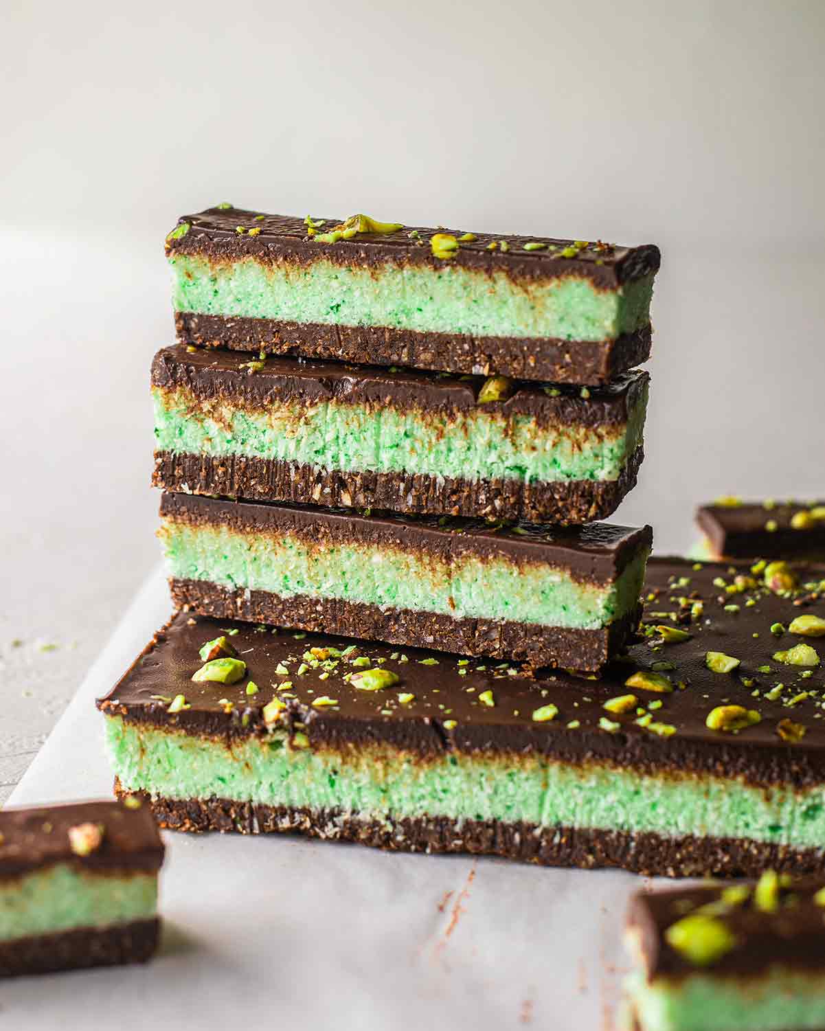 Stack of three individual chocolate mint bars balancing on an uncut slab of mint chocolate bars