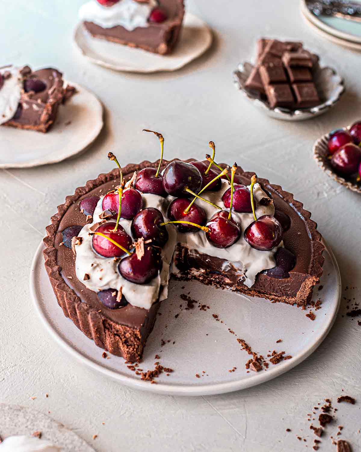 Vegan black forest tart on plate with two slices removed showing creamy texture of the ganache filling.