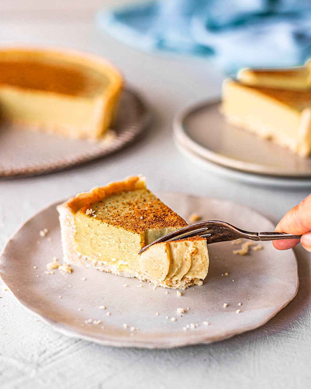 Close up of fork taking a bite out of one slice of the custard tart.