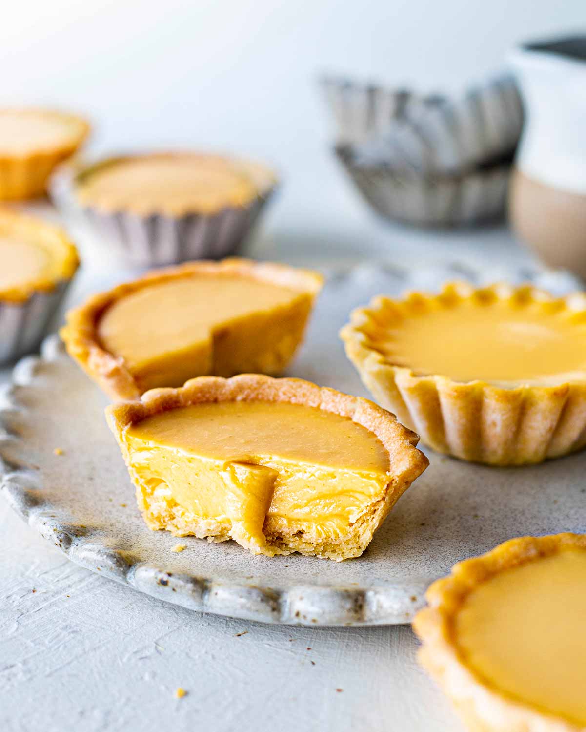 Close up of cut vegan egg tart showing silky custard interior and thin crumbly pastry.