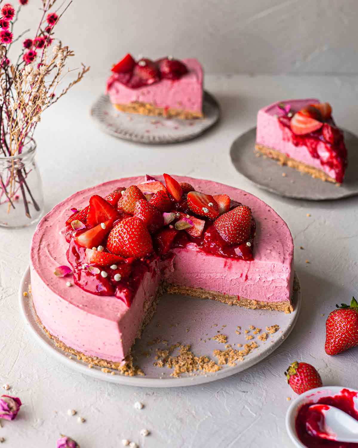 No bake vegan strawberry cheesecake on plate. Two slices cut out showing very creamy texture.