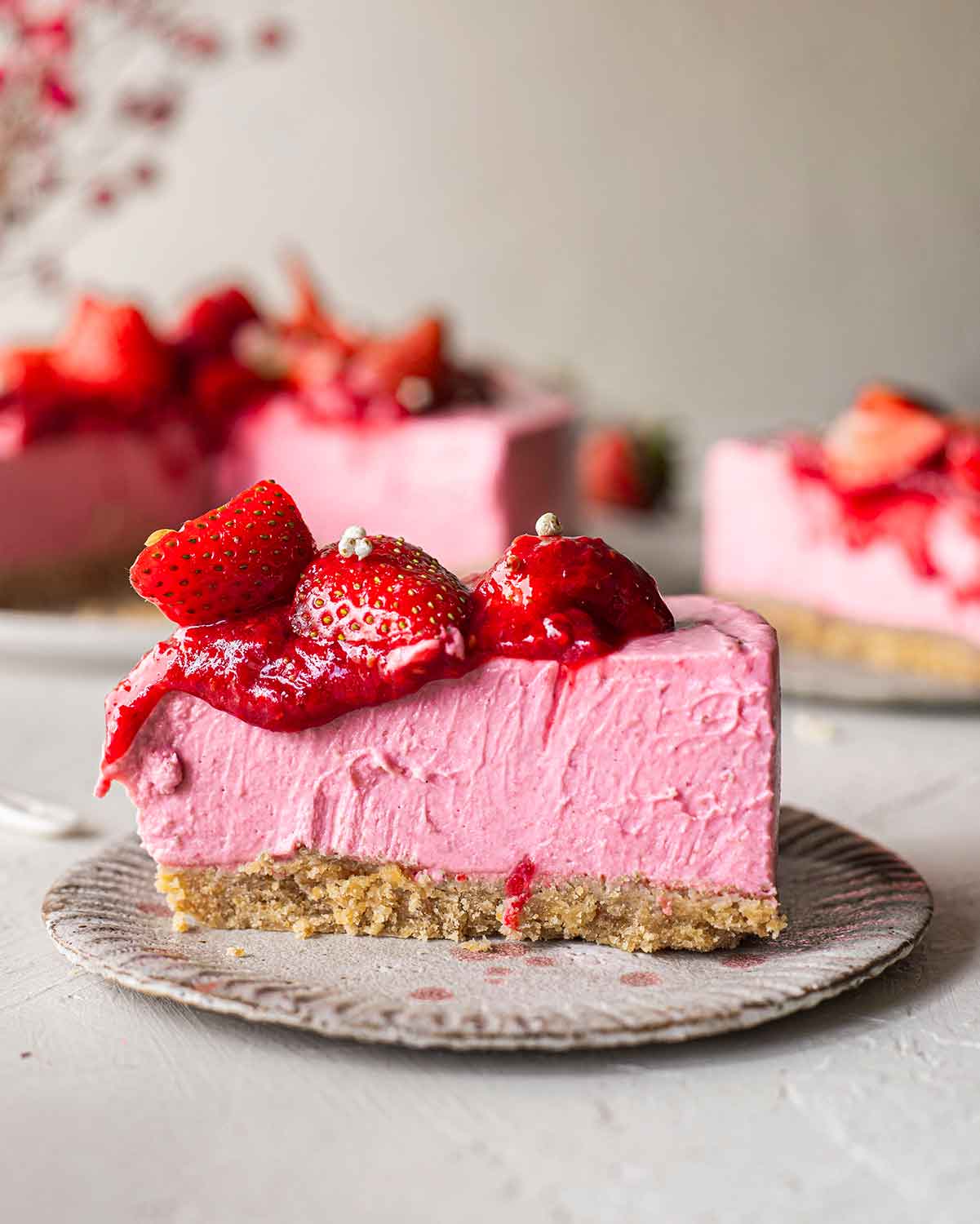 Close up of extremely creamy slice of strawberry cheesecake. Compote is dripping down the sides.