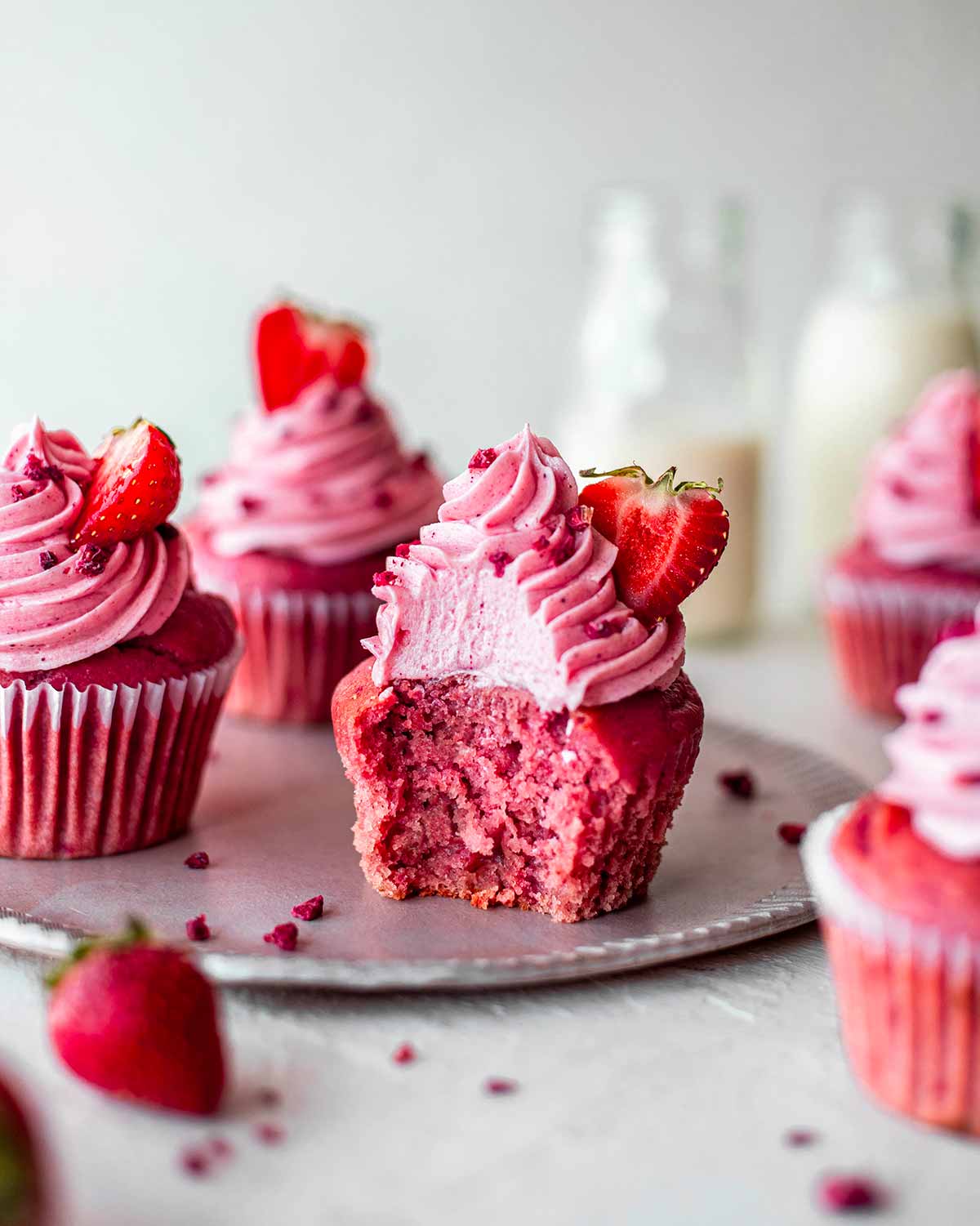 Pink strawberry cupcakes with creamy frosting on top.