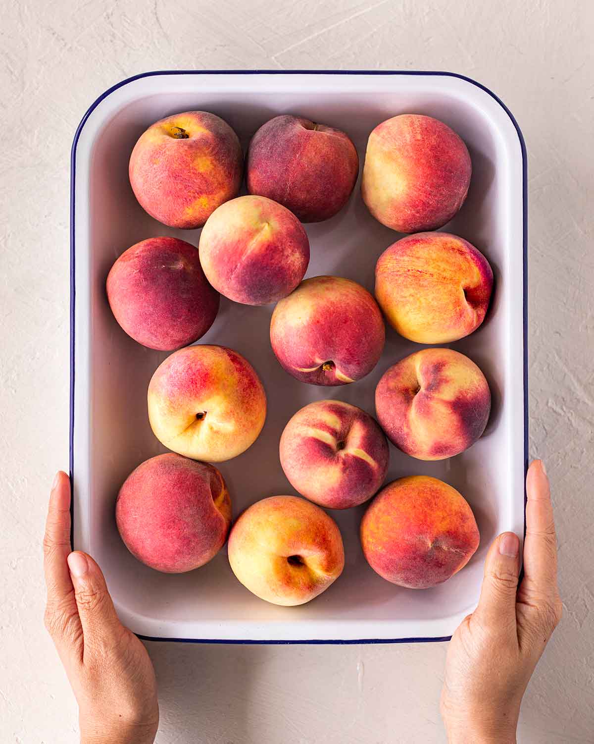 Flatlay of medium size peaches in casserole dish.