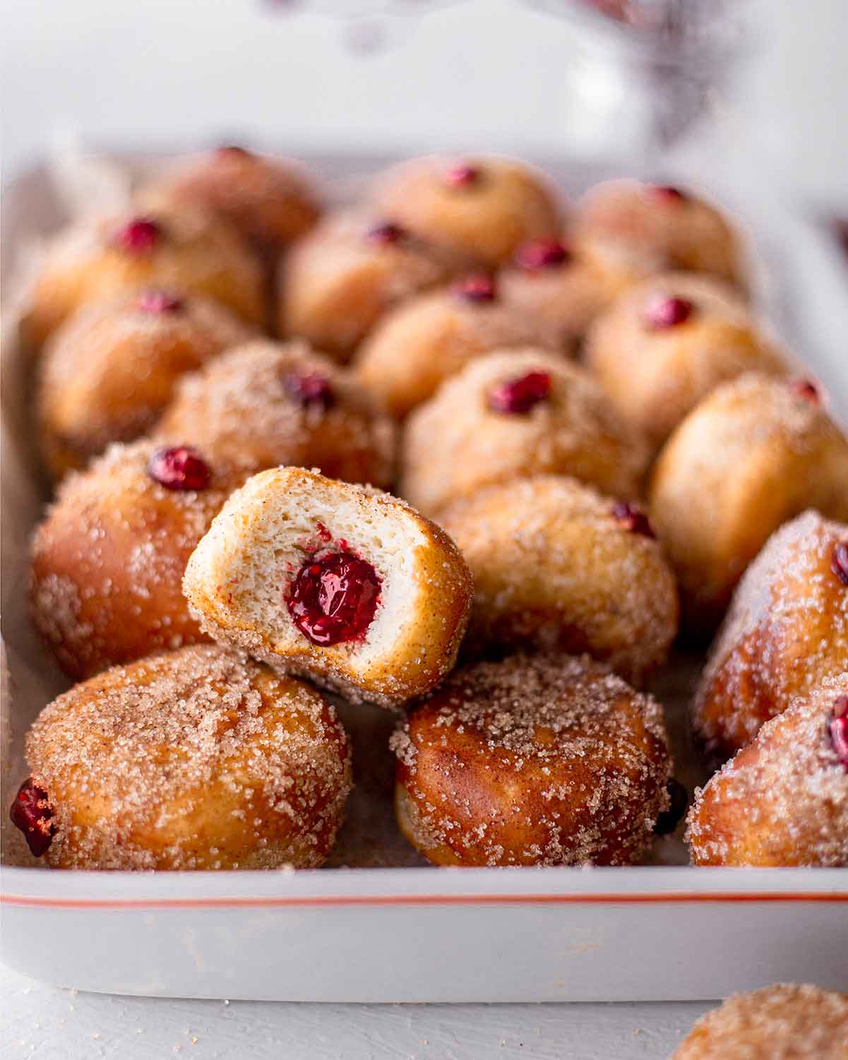 Close up of a vegan doughnut with bright raspberry jam (or jelly) in the cross section.