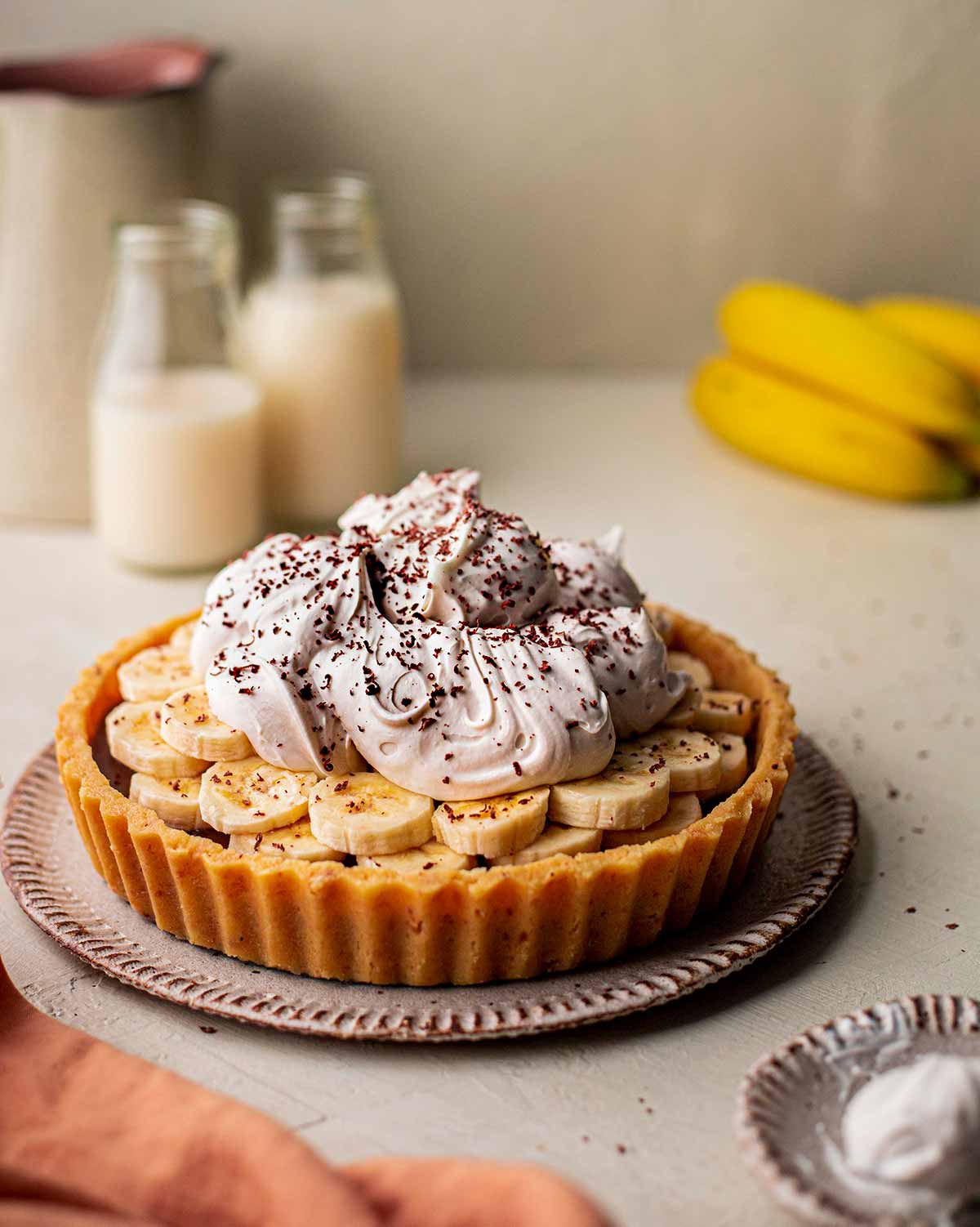 Photography of vegan banoffee pie with ingredients in foreground and background.