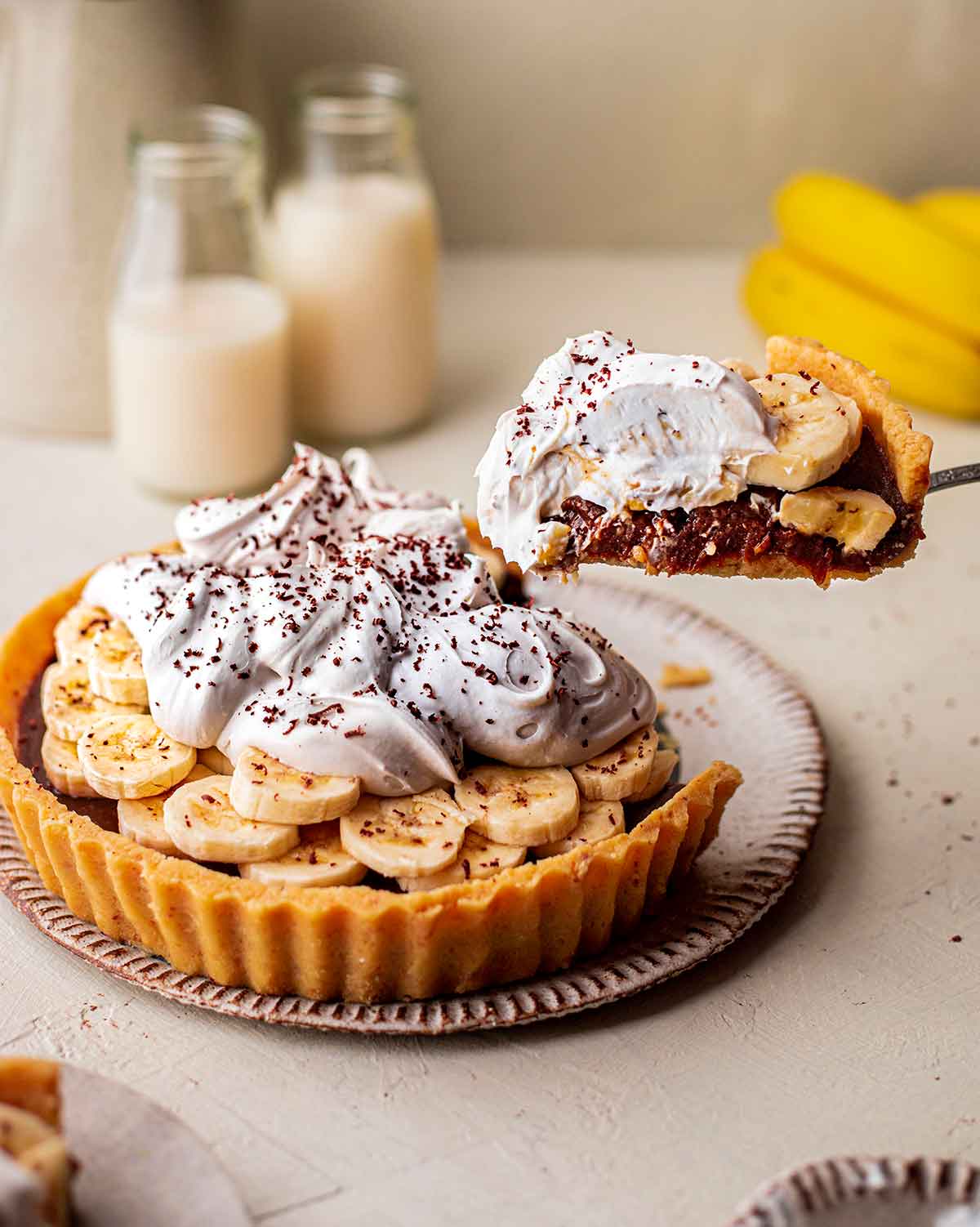 Vegan banoffee pie with slice coming out showing vegan caramel and coconut whipped cream.