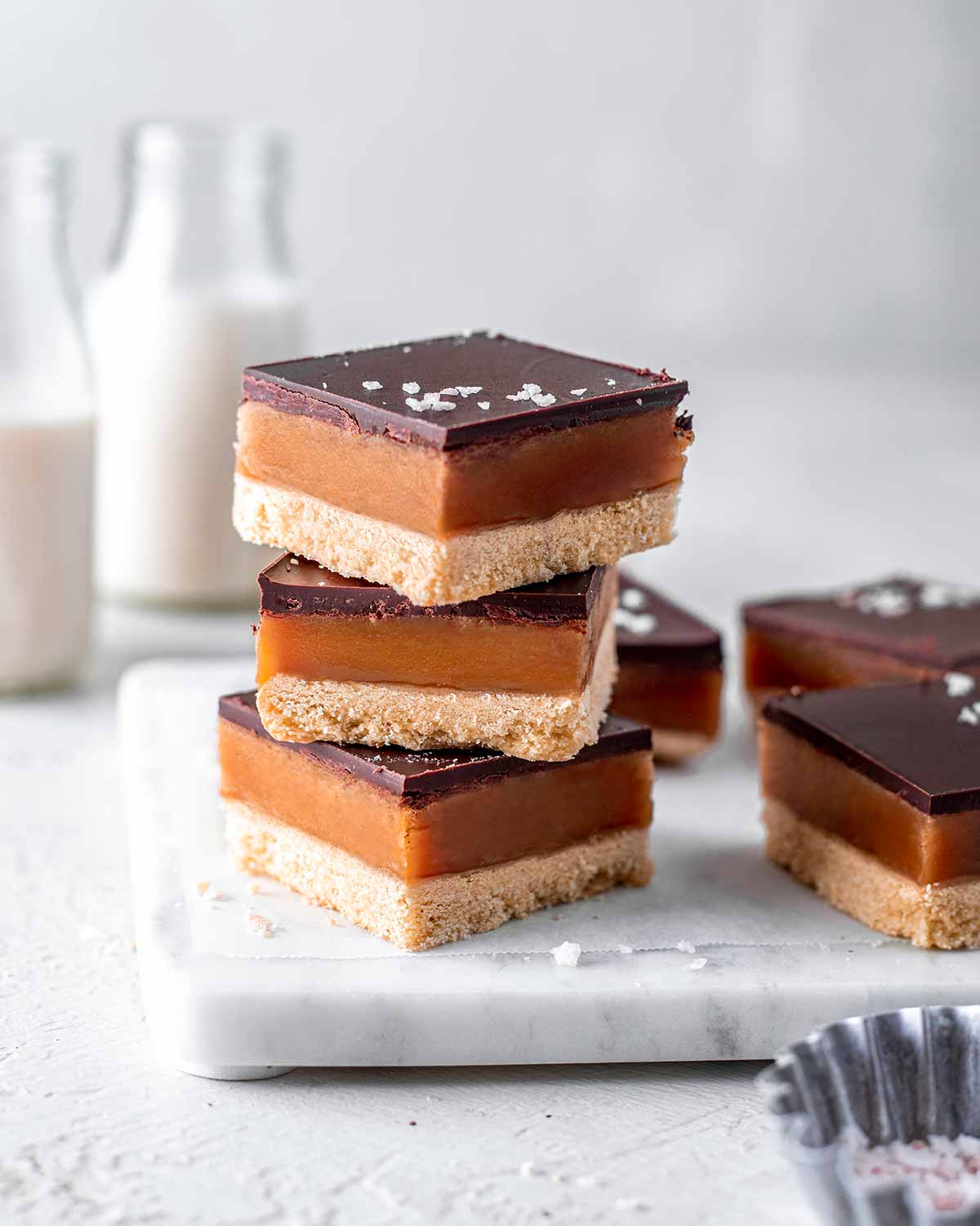 Stack of vegan millionaire bars on a white marble board.