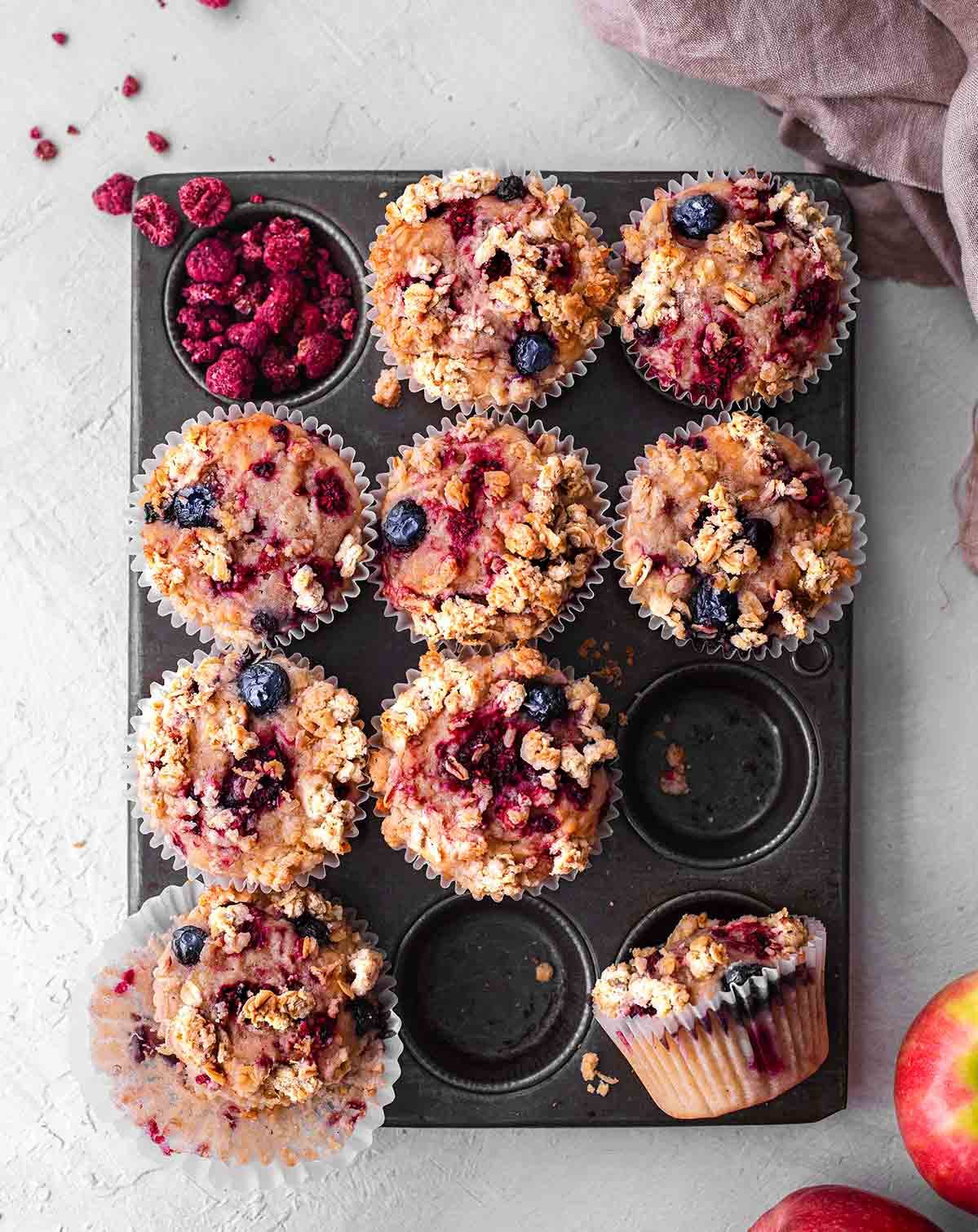 Flat-lay of vegan apple berry muffins in muffin tray.