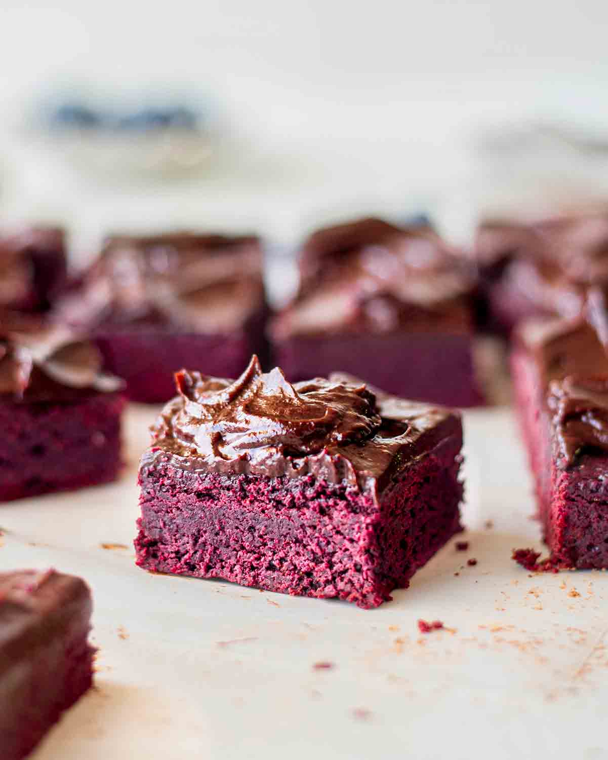 Close up of individual beetroot brownie with glossy chocolate avocado frosting.