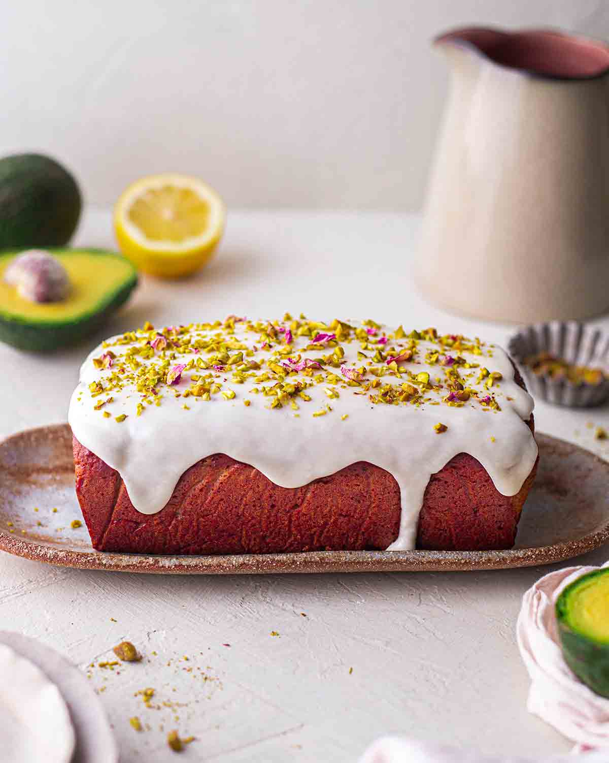 Side image of pistachio cake with white icing dripping down sides.