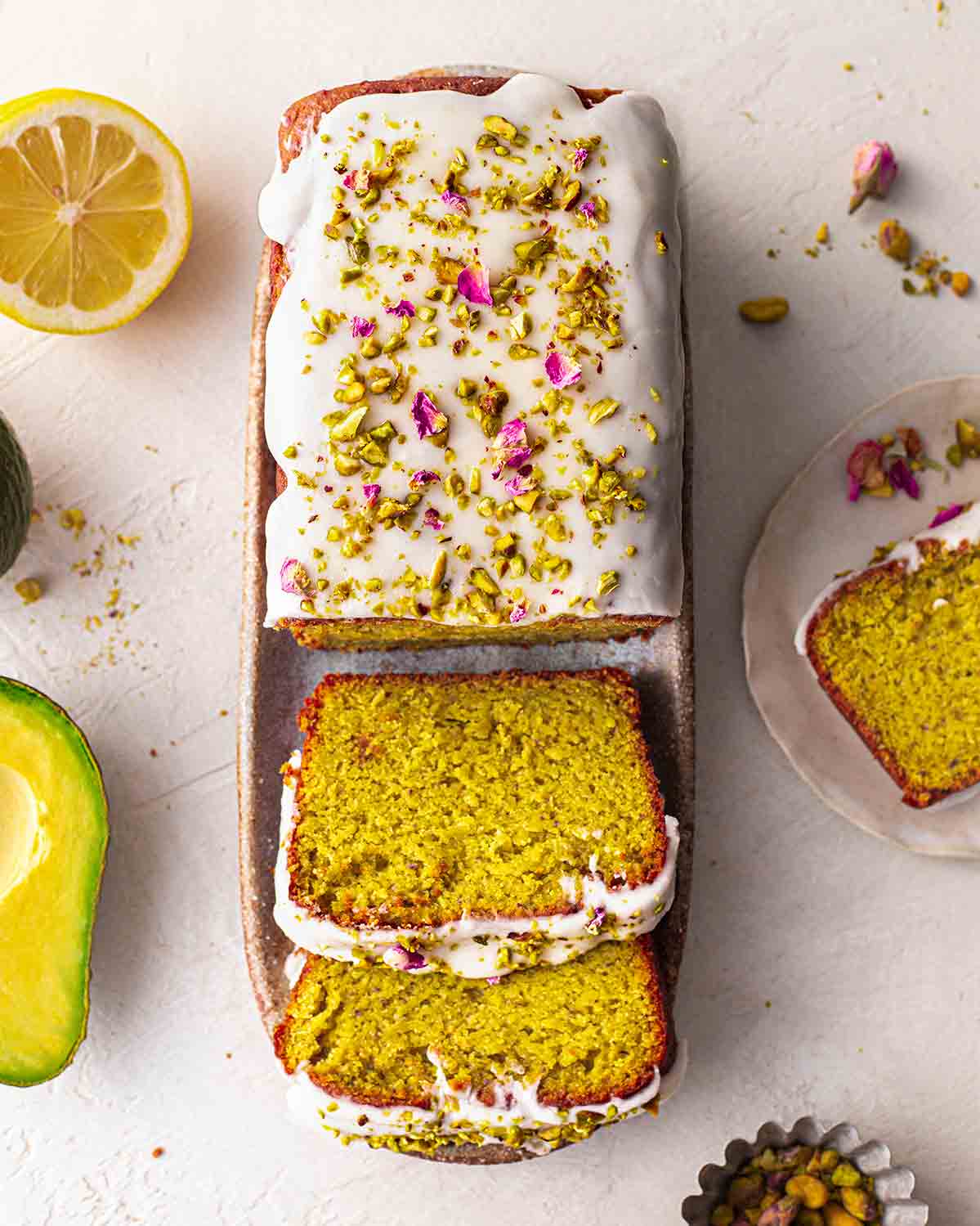 Bird's eye view of decorated pistachio cake with a few slices coming out showing subtle green colour and fluffy texture.