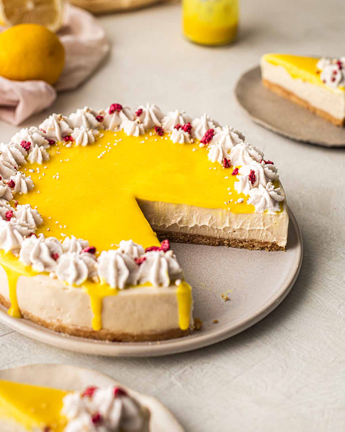 Vegan cheesecake topped with eggless lemon curd on a plate. Slice cut out of cheesecake revealing creamy texture.