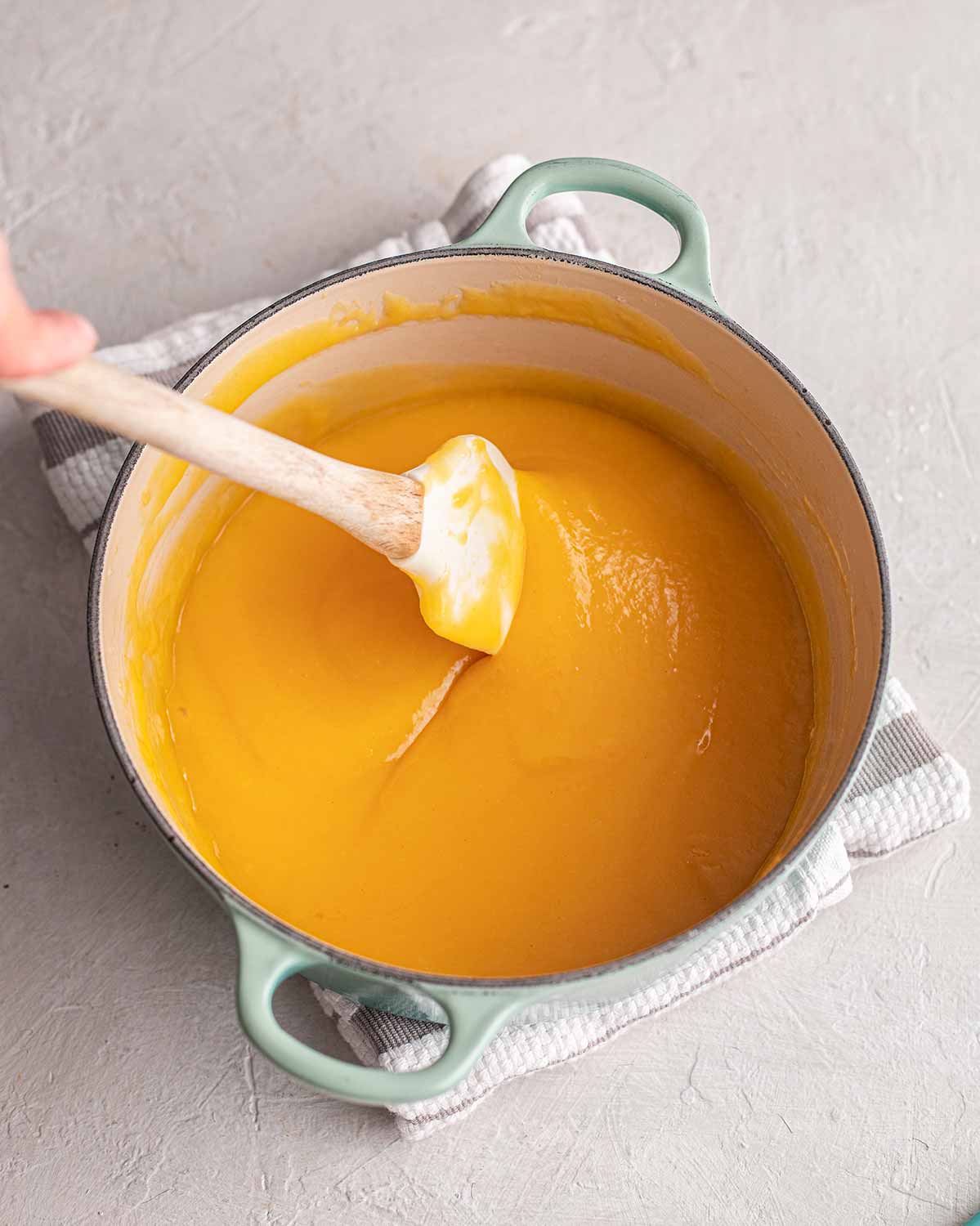 Thickened mandarin curd in saucepan.