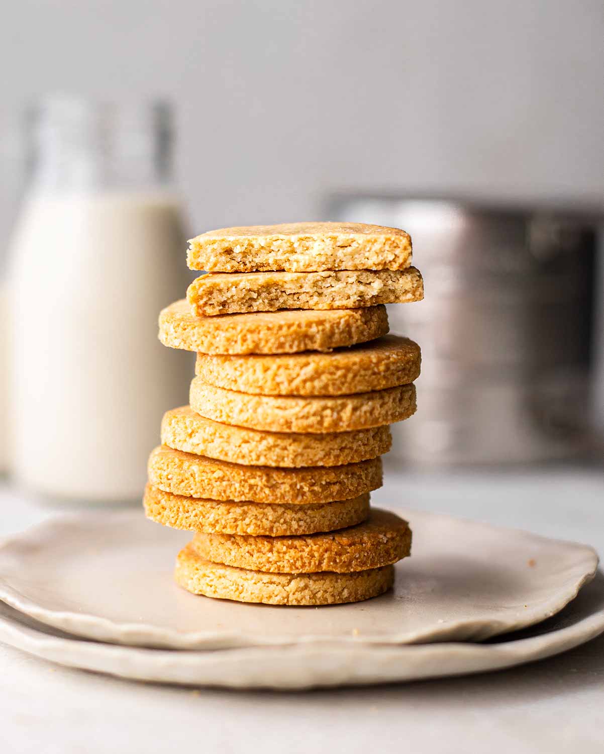 Close up of stack of cookies. Two cookies on top are in half revealing crumbly and golden texture.