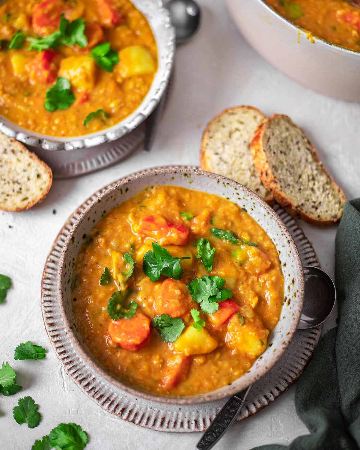 Side angle of red curry lentil soup in bowl.