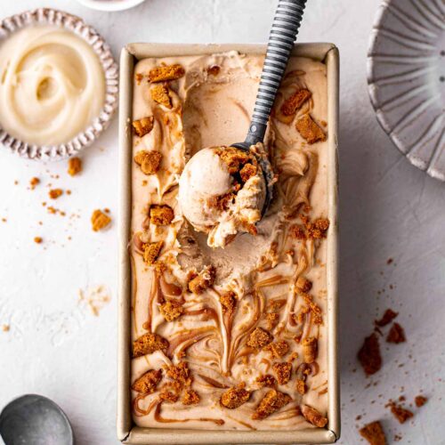 No churn vegan biscoff ice cream in a loaf pan with scoop of creamy ice cream coming out.