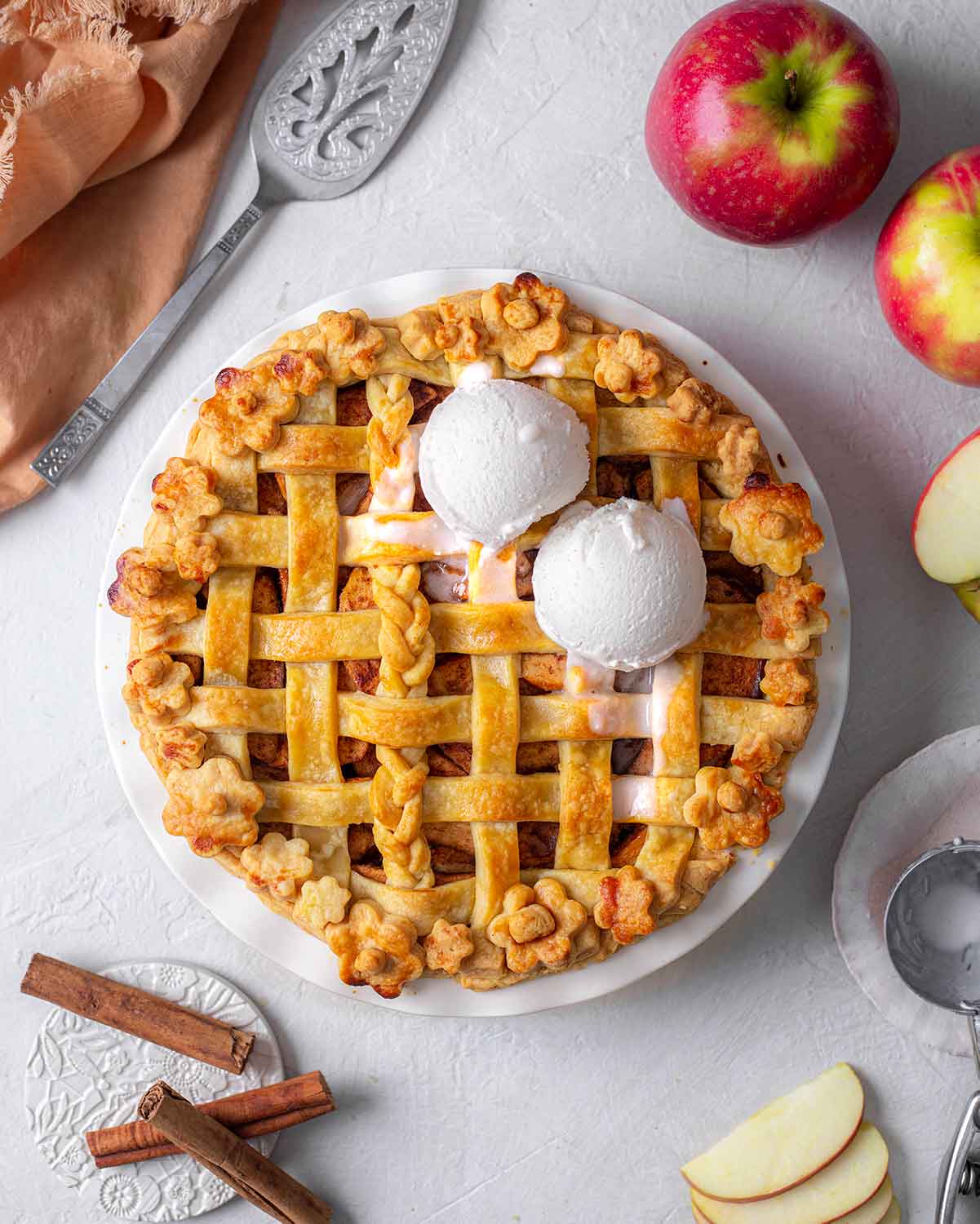 Golden apple pie with lattice design and two scoops of vanilla ice cream on top.