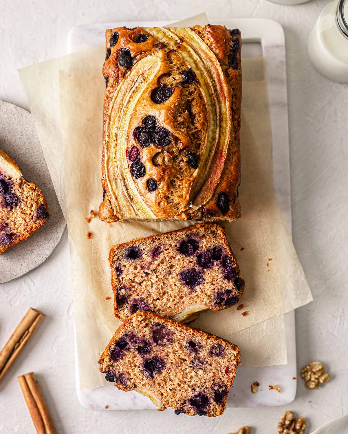 Overhead image of banana bread focusing on sliced banana and blueberry decorations.