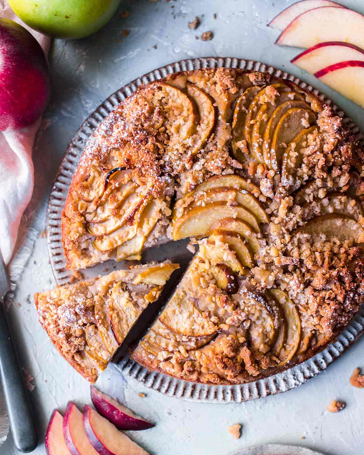 Close up of the topping of the vegan apple cake. Includes a rustic crumb topping and apple slices shaped in fans.