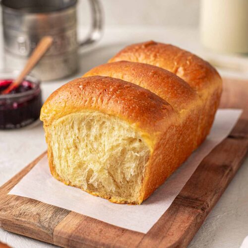 Buttery golden vegan brioche loaf on a serving board.