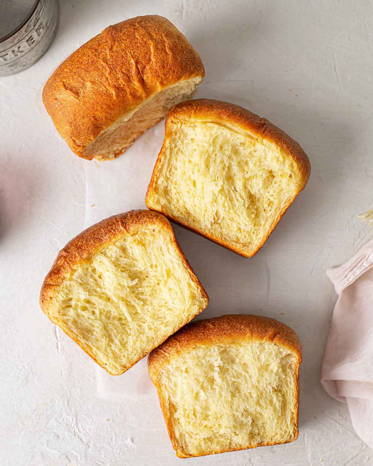 Flatlay of vegan brioche torn into 4 sections revealing fluffy and feathery interior.
