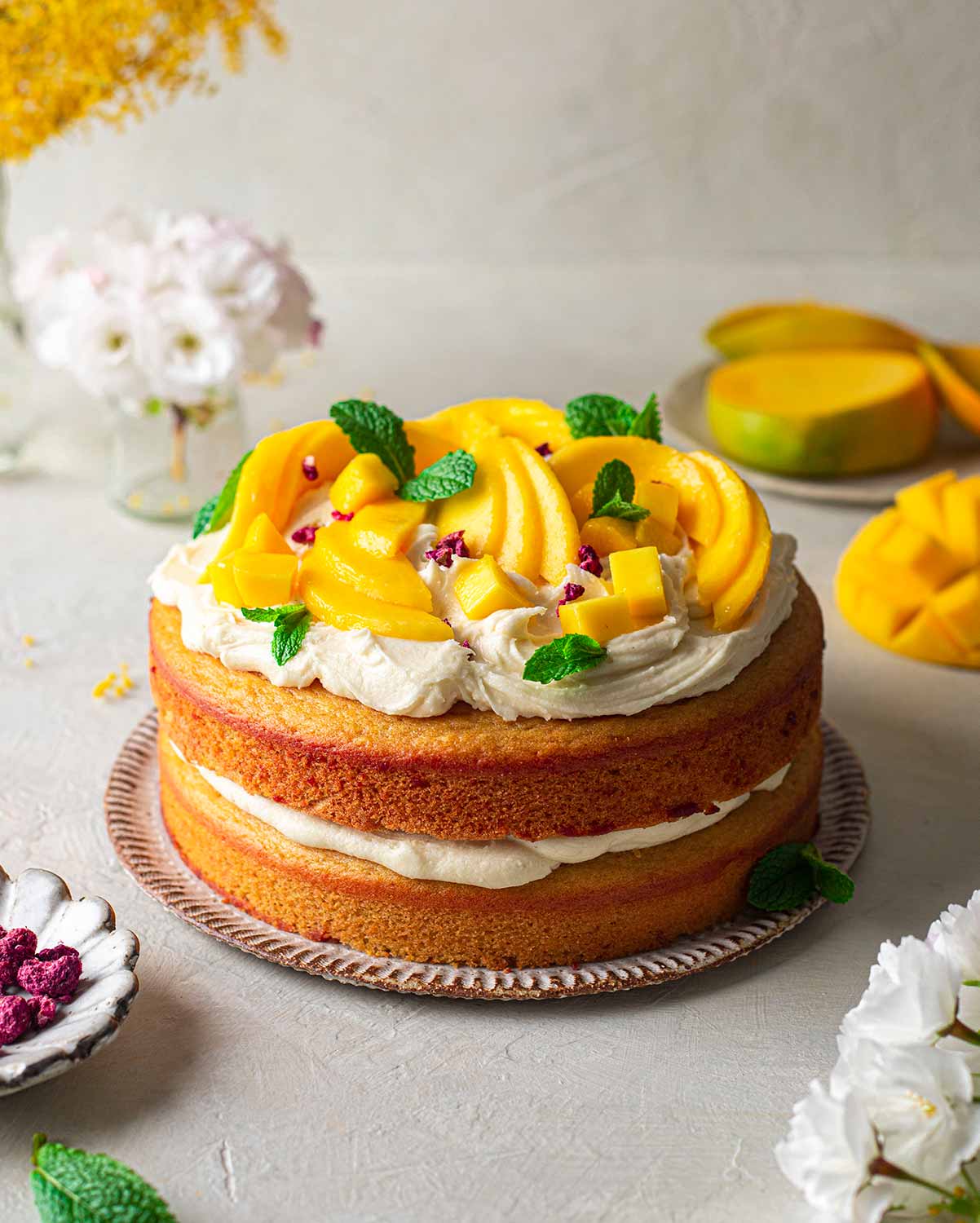 Vegan mango cake topped with rustic cream cheese frosting and slices of fresh mango.