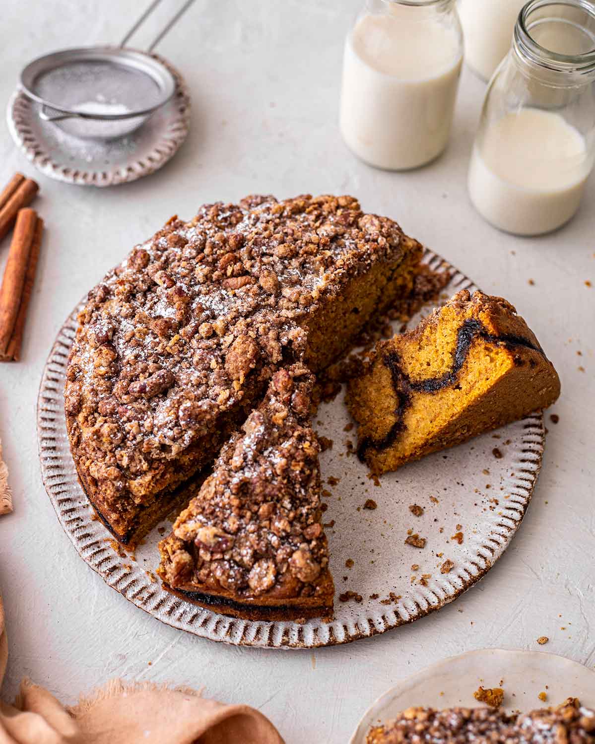 Vegan pumpkin coffee cake with two slices taken out revealing the cinnamon sugar layer in the middle of the cake.