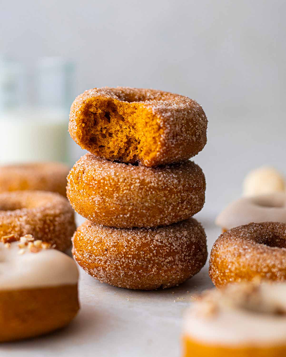 Stack of sugar coated and thick donuts showing golden orange and fluffy interior.