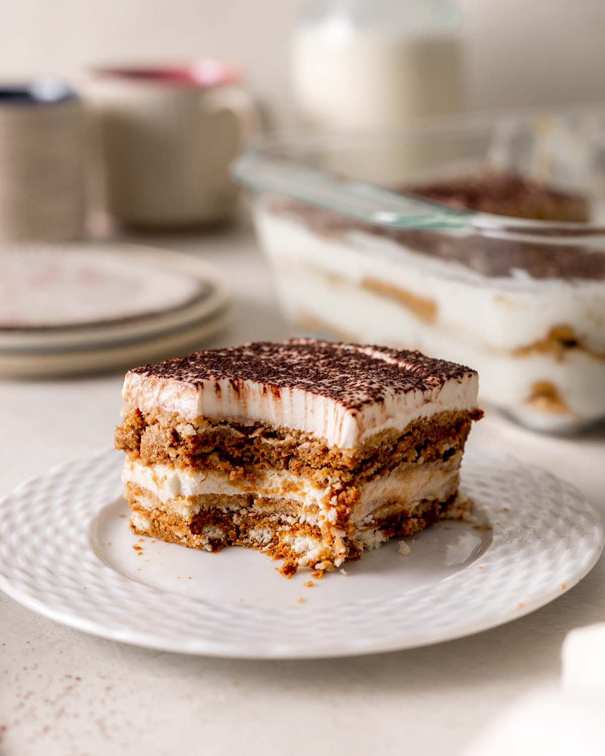 Close up of individual slice tiramisu where a spoon has removed the corner revealing the delicious layers.