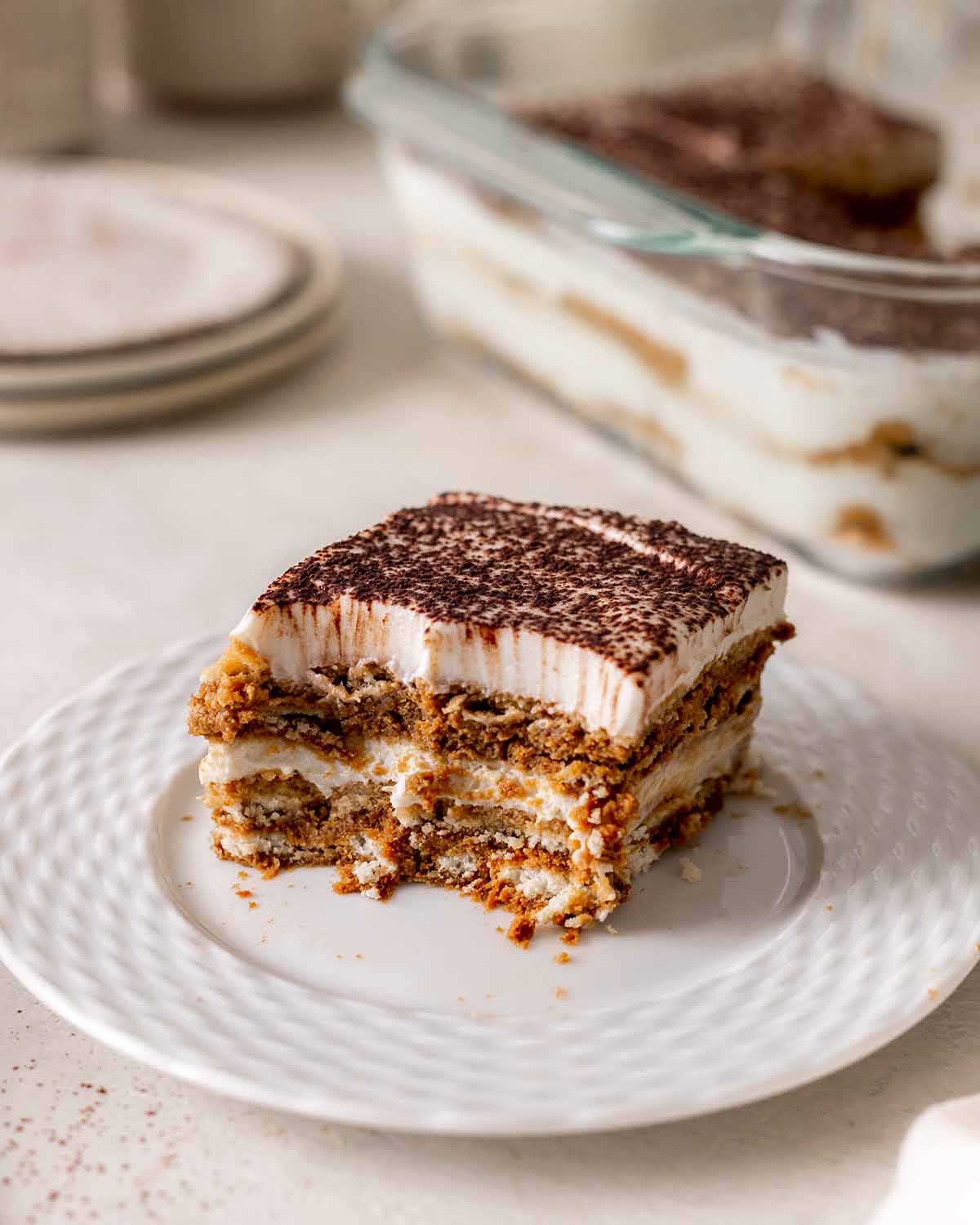 Close up of individual serve of tiramisu with two bites taken out.