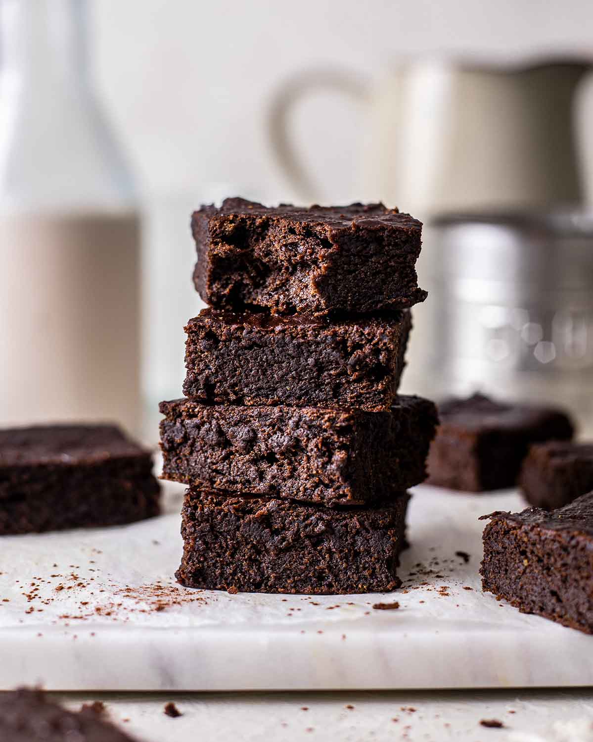 Stack of fudgy and dark vegan protein brownies with bite out of top brownie showing texture.