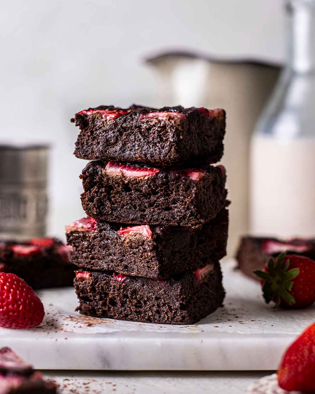 Stack of vegan protein brownies with strawberries on top of each brownie.